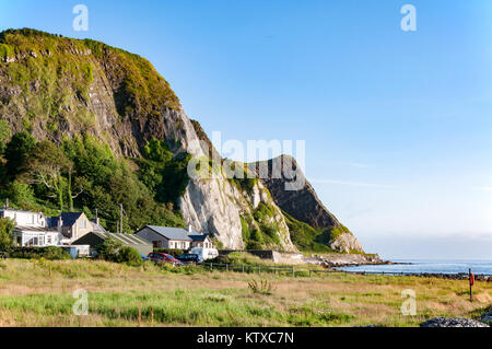 Der östlichen Küste von Nordirland mit Felsen, Hügel und Häuser im Antrim Küstenstraße, alias Causeway Coastal Route. Stockfoto