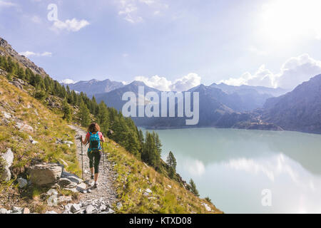 Wanderer auf dem Weg in Richtung Rifugio Bignami neben dem Dam und Wasserbecken der Alpe Gera, malenco Tal, Valtellina, Lombardei, Italien, Europa Stockfoto