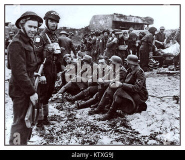 D-Day, 6. Juni 1944 WW2 Normandie deutsche Kriegsgefangene. Britische 5th Bataillon Royal Berkshire Regiment auf Juno Beach Normandie, bewachen Gefangene der Deutschen KRIEGSGEFANGEN des Krieges mit im Hintergrund verletzt zu übergeben Stockfoto