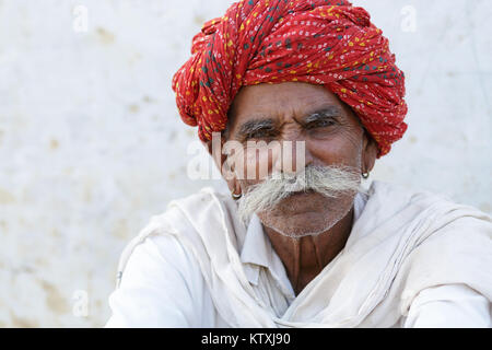Portrait von hochrangigen indischen Mann im weißen Outfit mit großen Schnurrbart, das Tragen der roten Turban, Dorf in der Nähe von Pushkar, Indien. Stockfoto
