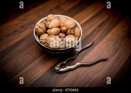 Eine Schüssel gemischten ganze Nüsse in der Schale, einschließlich Walnüsse, Haselnüsse, Mandeln und Pekannüsse mit Mutter Cracker Stockfoto