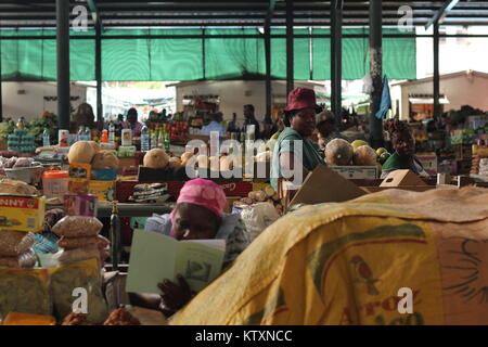 Frauen in einem traditionellen städtischer Markt von Maputo, Mosambik Verkauf von verschiedenen Produkten und einer Frau, die in der Front, ein Buch zu lesen. Stockfoto