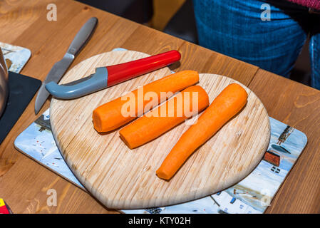 Saubere frische Karotten mit Messer auf Herz geformte Holz Schneidebrett. Stockfoto