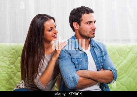 Junges Paar sitzt auf einem Sofa zu Hause. Der Mensch ist wütend. Stockfoto