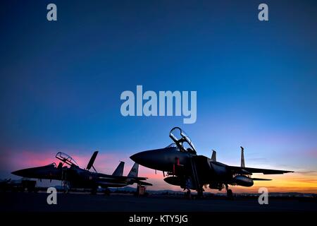 Die Sonne über zwei F-15E Strike Eagle Jet Fighter Aircraft auf der Landebahn von der Nellis Air Force Base in der Nacht während der Übung Rote Fahne, 10. Februar 2014 in der Nähe von Las Vegas, Nevada. Stockfoto