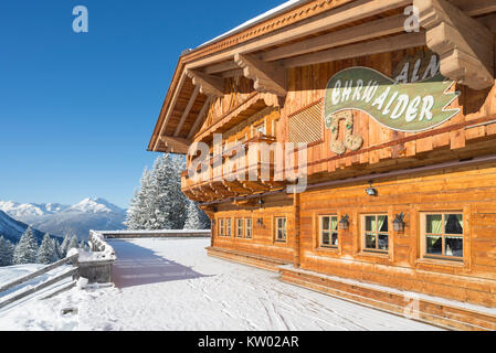 Alpine Chalet aus Holz auf der Ehrwalder Alm Skigebiet von einem sonnigen verschneiten Winterlandschaft umgeben, Tirol, Österreich Stockfoto