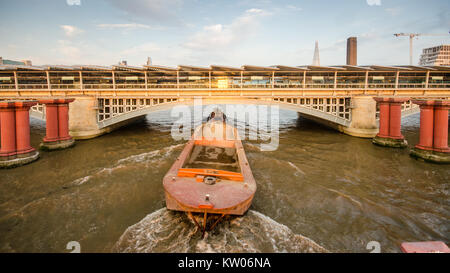 London, England, UK - 15. September 2014: Ein Schlepper schleppt ein cargo Schiff auf der Themse unter Blackfriars Railway Station in der Londoner City. Stockfoto