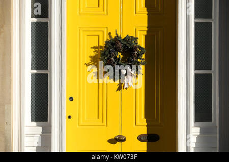 Weihnachten ein Kranz befestigt, um ein helles yellw lackierte Tür. Sein ein altes viktorianisches Haus in Clifton, Bristol auf einen hellen klaren Wintertag Stockfoto