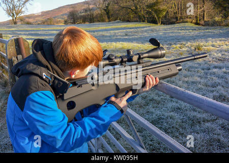 Teenager feuern ein Luftgewehr auf Ackerland an einem kalten, frostigen Tag. Stockfoto