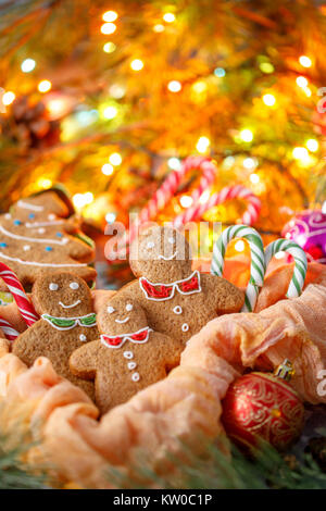 Köstlichkeiten im Hintergrund von blinkenden Girlanden. Eine wunderschöne Weihnachtskarte. Traditionelle Weihnachten Ingwer Gebäck in Form von kleinen Männer und C Stockfoto