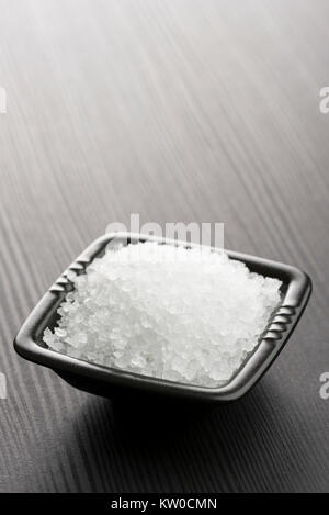 Natürliches Salz in schwarz Schüssel auf hölzernen Tisch Stockfoto