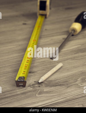 Nahaufnahme von Maßband, Schraubenzieher und Bleistift auf einem hölzernen Hintergrund Stockfoto