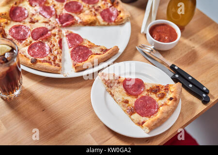 Frische Pizza mit Salami auf hölzernen Tisch im Restaurant. Stockfoto