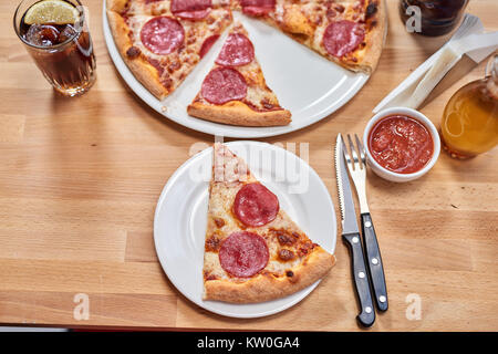 Frische Pizza mit Salami auf hölzernen Tisch im Restaurant. Stockfoto