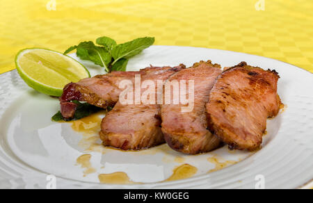 Vier Folie gegrillten geräuchertes Schweinefleisch in einer weißen Schüssel und eine Zitrone Folie serviert. Stockfoto