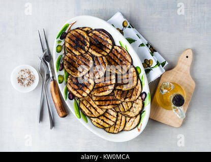 Gegrillte Auberginen gewürzt mit Olivenöl auf einem weißen Tisch aus Stein Stockfoto
