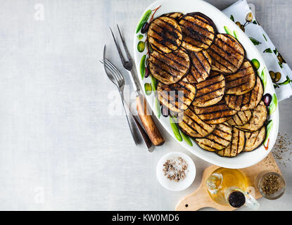 Gegrillte Auberginen gewürzt mit Olivenöl auf einem weißen Tisch aus Stein Stockfoto