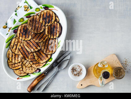 Gegrillte Auberginen gewürzt mit Olivenöl auf einem weißen Tisch aus Stein Stockfoto