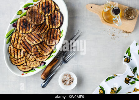Gegrillte Auberginen gewürzt mit Olivenöl auf einem weißen Tisch aus Stein Stockfoto