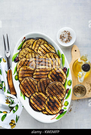 Gegrillte Auberginen gewürzt mit Olivenöl auf einem weißen Tisch aus Stein Stockfoto