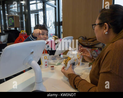 Eine Mutter und Sohn genießen Sie Frühstück ata McDonald's Fast Food Restaurant. Das Restaurant ist mit Tablet Pcs für Unterhaltung ausgestattet. Stockfoto