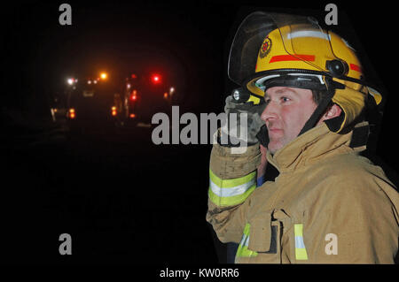 Greymouth, Neuseeland, ca. 2006: Feuerwehrmann verwendet eine Fackel auf dem Feld bei einem abendlichen Buschfeuer in der Nähe von Greymouth Westla, Signal Stockfoto