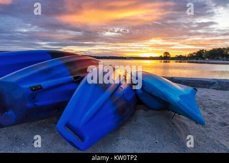 Sommer Kajak Sonnenaufgang. Reihe von bunten Kajaks säumen die Ufer von einem Sandstrand wie Sunrise Farben spiegeln sich in den ruhigen Wassern des Lake Michigan. Stockfoto