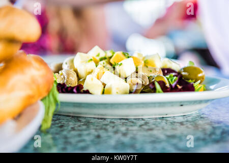 Makro Nahaufnahme von Salat auf Teller im Restaurant mit Champignons, Käse-Quadrate, Oliven und Grüns Stockfoto