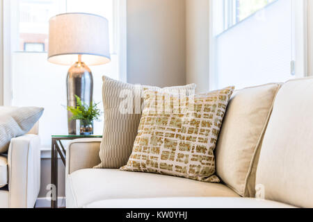 Nahaufnahme von zwei Kissen auf der Couch oder Sofa von hellen Fenster in der modernen Wohnung, Haus oder Haus mit Inszenierung der Großen beige, neutralen weißen Farben, Lampe Stockfoto