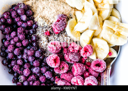 Gefrorene Heidelbeeren, Himbeeren, Banane, Maca und Chia Samen Belag auf haferflockenbrei Stockfoto