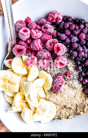 Gefrorene Heidelbeeren, Himbeeren, Banane, Maca und Chia Samen Belag auf haferflockenbrei Stockfoto