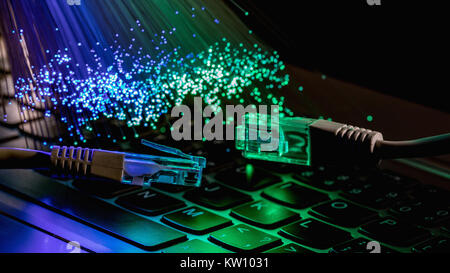 Netzwerkkabel closeup mit LWL-Hintergrund, Farbe LWL-Hintergrund mit notebookk, Fiberoptik Licht abstrakt Hintergrund Stockfoto