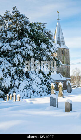 Kirche St. Bartholomä und Grabsteine auf dem Friedhof in der Dezember Schnee. Notgrove, Cotswolds, Gloucestershire, England Stockfoto