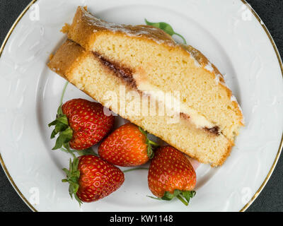 Gebackene Victoria Biskuitteig mit frischen Erdbeeren und Sahne auf schwarzem Hintergrund Stockfoto