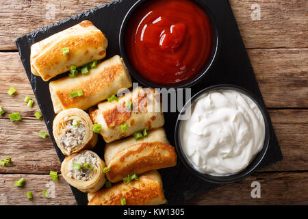 Pfannkuchen Brötchen mit Hähnchen, Käse und Champignons close-up und Saucen auf dem Tisch. Horizontal oben Ansicht von oben Stockfoto