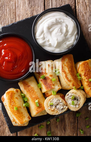 Pfannkuchen Brötchen mit Hähnchen, Käse und Champignons close-up und Saucen auf dem Tisch. Vertikal oben Ansicht von oben Stockfoto