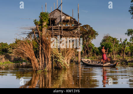 Ein Fischer in einem Boot in der Nähe des Hauses in einem Fischerdorf am See Tonle Sap, Kambodscha Stockfoto