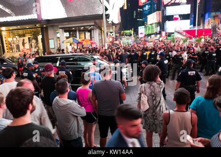 Während ein Schwarzes Leben Angelegenheit Protest in New York City's Times Square nach dem schießenden Todesfälle von Alton Sterling und Philando Kastilien, einem schwarzen SUV geht schnell durch eine Kreuzung als Aktivisten Datenverkehr blockieren und gegen eine Linie des New York Police Department (NYPD) Polizei und Touristen Blick auf 2016. Stockfoto