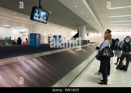 Reisende am Newark International Airport sehen Sie eine Nachrichtensendung über einen neuen Aufnahmen beim Warten auf Ihre Koffer am Gepäckkarussell, Newark, New Jersey, Juli 2016 zu kommen. Stockfoto