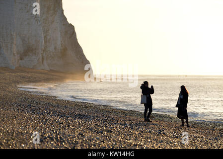 Touristen unter selfies unterhalb der berühmten Sieben Schwestern Kreidefelsen am Cuckmere Haven, East Sussex, Großbritannien Stockfoto