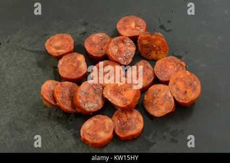 In Scheiben geschnittene Getrocknete geheilt Chorizo Wurst aus Schweinefleisch auf dem Schwarzen Brett als Zutat in Vorbereitung zum Kochen Stockfoto