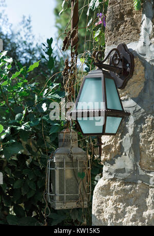 Alte Lampen hängen an der Mauer aus Stein Stockfoto