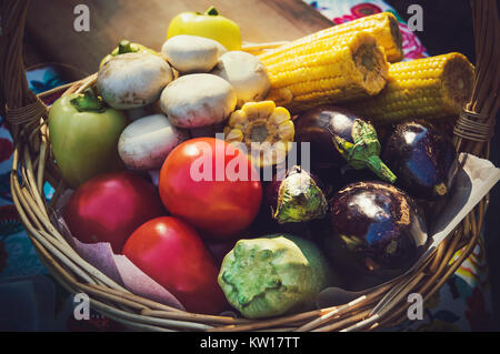 Gemüse im Weidenkorb. Herbst Ernte: Zucchini, Pilze, Auberginen, Tomaten und Mais in Weidenkorb Stockfoto