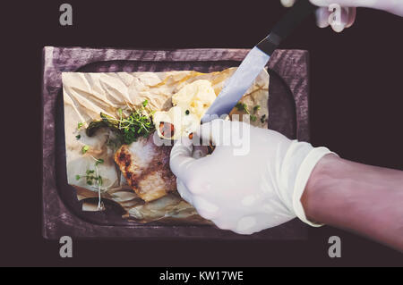 Prozess der Küche Fisch. Hände Köche in saubere, weiße Handschuhe setzt eine Sauce zu gegrilltem Fisch. Die Aussicht von oben. Stockfoto