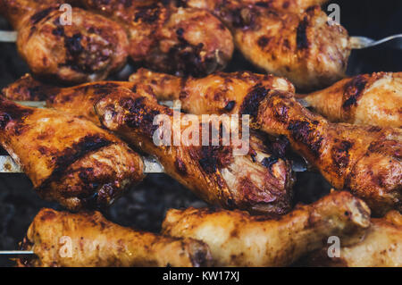 Gegrilltes Hähnchen am Spieß mit einem leckeren knusprig gebratener Kruste. Die Aussicht von oben. Hot BBQ Holzkohle flammende Grill Close-up. Stockfoto
