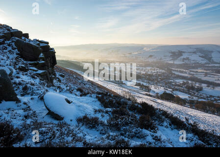 Dawn an Bamford Kante im Peak District an einem kalten Wintermorgen. Eine alte verlassene Mühlstein im Schnee bedeckt. Stockfoto