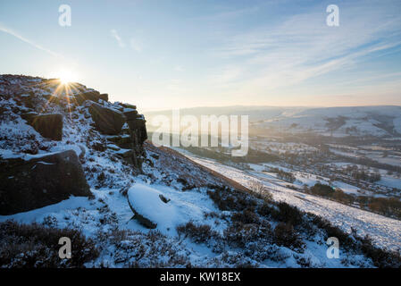 Dawn an Bamford Kante im Peak District an einem kalten Wintermorgen. Eine alte verlassene Mühlstein im Schnee bedeckt. Stockfoto