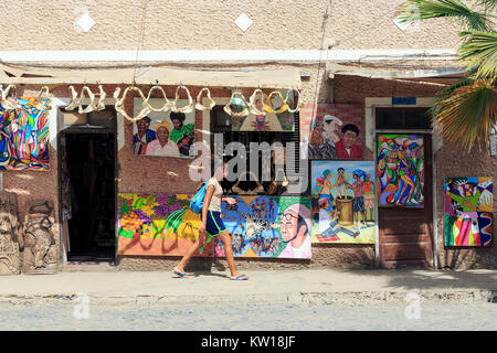 Junge lokale Mädchen hinter einem touristischen Souvenirshop mit Kunstwerken und Haie Backen, Santa Maria, Sal, Salina, Kap Verde, Afrika Stockfoto