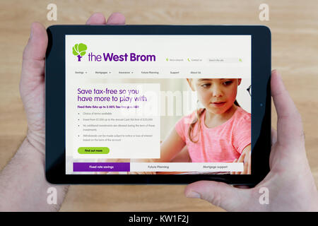 Ein Mann schaut auf die Westbrom Building Society Website auf seinem iPad tablet device, Schuß gegen einen hölzernen Tisch top Hintergrund (nur redaktionelle Nutzung) Stockfoto