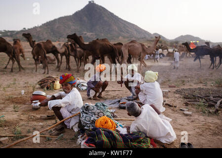 Szene in Pushkar Camel Fair, Männer rauchen Zigarren, um Kamin am Ende des Handelstages, Ajmer, Pushkar, Rajasthan, Indien Stockfoto